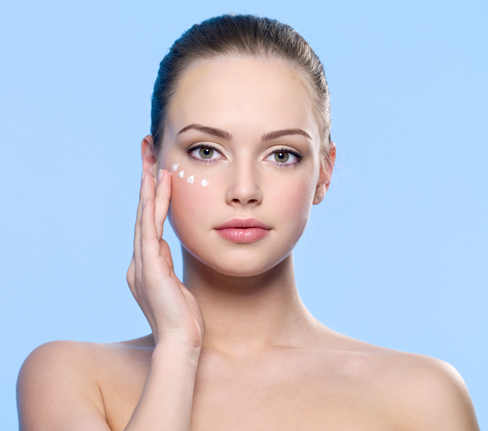 portrait young adult girl applying cream her skin around eyes blue